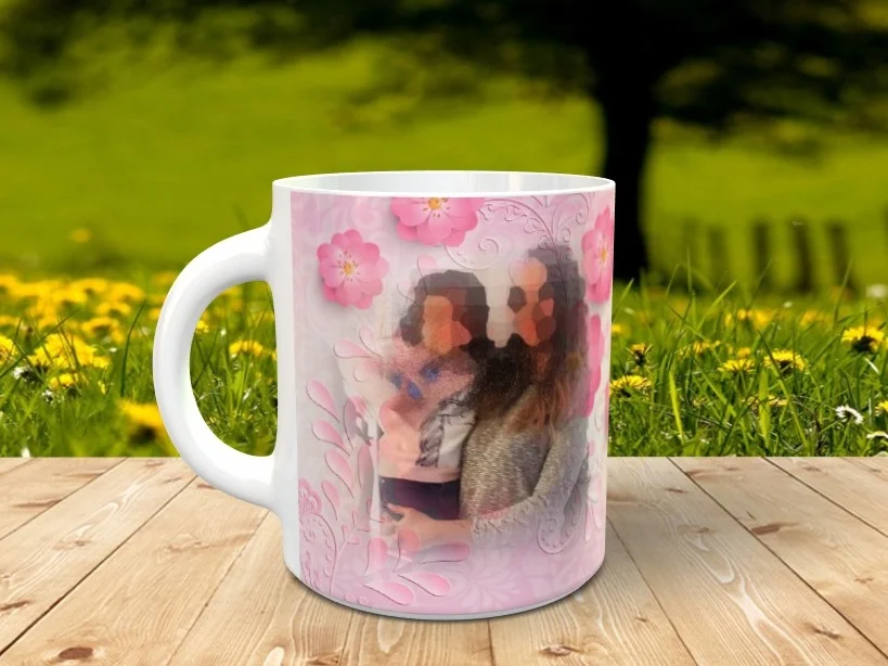 Taza blanca personalizable con diseño de flores rosas y una fotografía integrada, apoyada sobre una superficie de madera ante un fondo natural difuminado.
