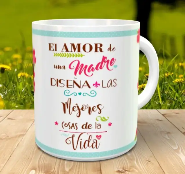 Taza blanca personalizable con un mensaje dedicado al amor de madre en tonos marrones, rosas y turquesas, apoyada sobre listones de madera con un fondo natural desenfocado.