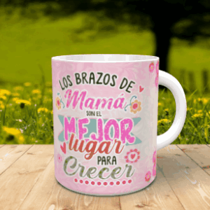 Taza blanca personalizable con un diseño frontal dedicado a los abrazos de mamá sobre un fondo rosa con flores y corazones, apoyada en una superficie de listones de madera ante un paisaje natural difuminado.