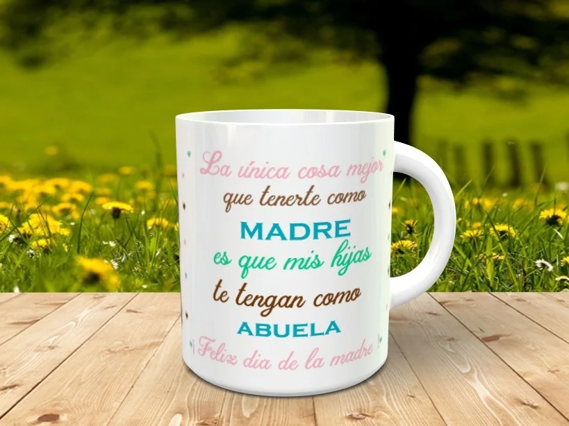Taza blanca personalizable con un mensaje dedicado a madres y abuelas en tonos rosas, marrones y azules, apoyada sobre madera con fondo natural.