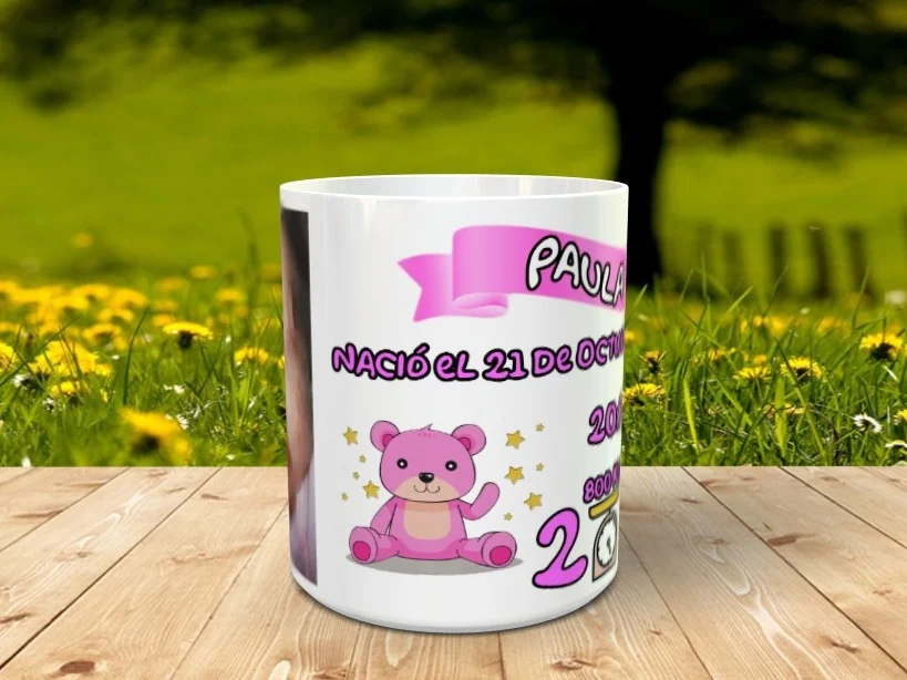 Taza blanca personalizable con diseño de recién nacida, nombre Paula, osito rosa y datos de nacimiento, sobre listones de madera.