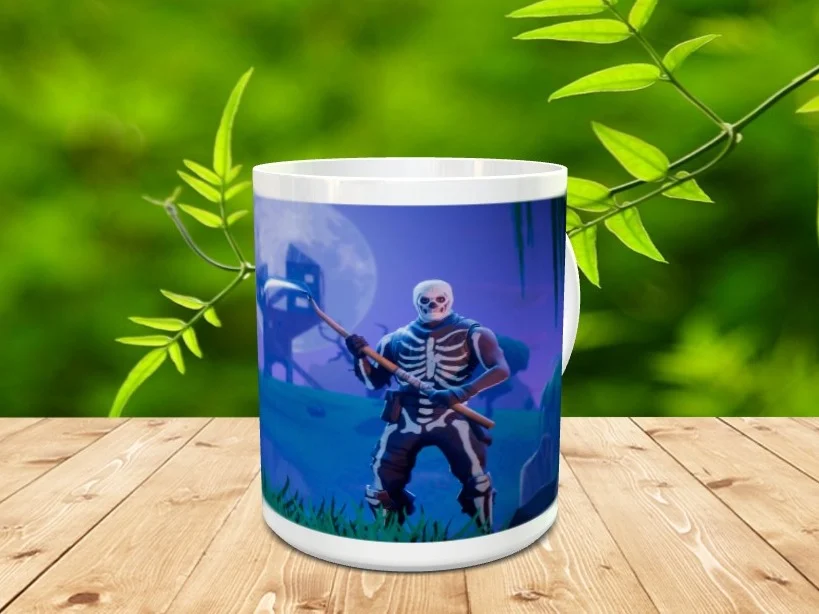 Taza de cerámica blanca con la imagen de un personaje esquelético de Fortnite sobre fondo azul oscuro, apoyada en una superficie de madera.