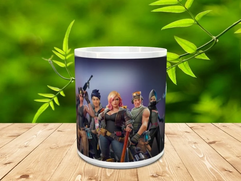 Taza de cerámica blanca decorada con varios personajes del videojuego Fortnite sobre fondo oscuro, colocada sobre una superficie de madera.