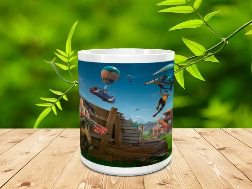 Taza de cerámica blanca ilustrada con personajes y elementos del videojuego Fortnite, apoyada sobre una superficie de madera.