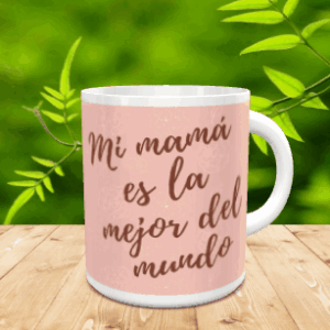 Taza blanca de cerámica personalizada con fondo rosa y texto Mi mamá es la mejor del mundo, sobre superficie de madera con vegetación de fondo.