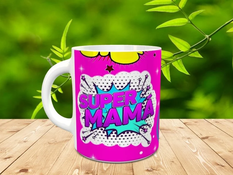 Taza blanca de ceramica personalizada con un diseño de estilo cómic en tonos fucsia y azul con el texto SUPER MAMA, sobre una superficie de madera.