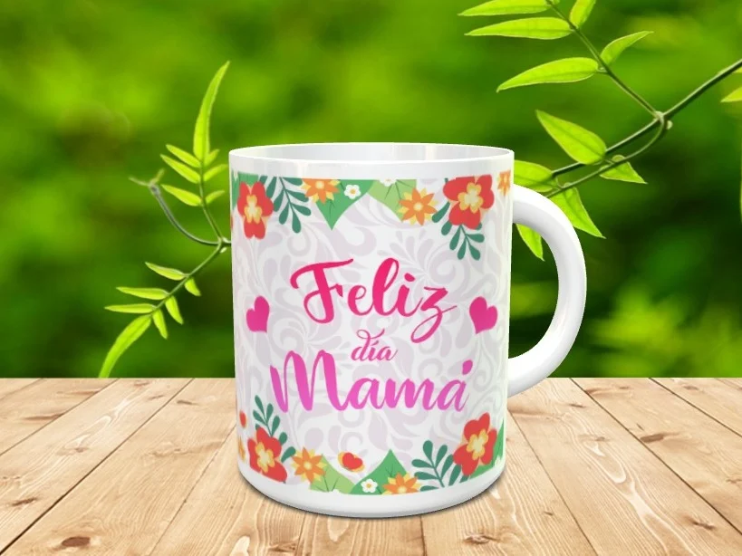 Taza blanca de cerámica personalizada con el texto Feliz día Mamá, motivos florales y corazones sobre un fondo de tablones de madera.