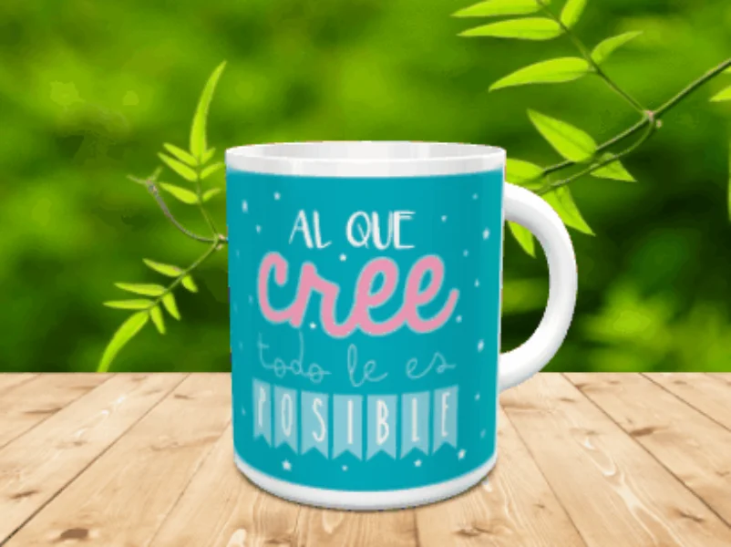 Taza de cerámica blanca con diseño motivacional sobre fondo azul y texto en tonos claros, apoyada sobre una superficie de madera.