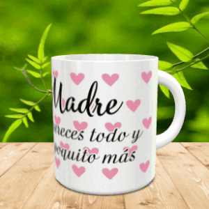 Taza blanca de cerámica personalizada con el texto Madre te mereces todo y un poquito más y pequeños corazones rosados, sobre fondo de madera.