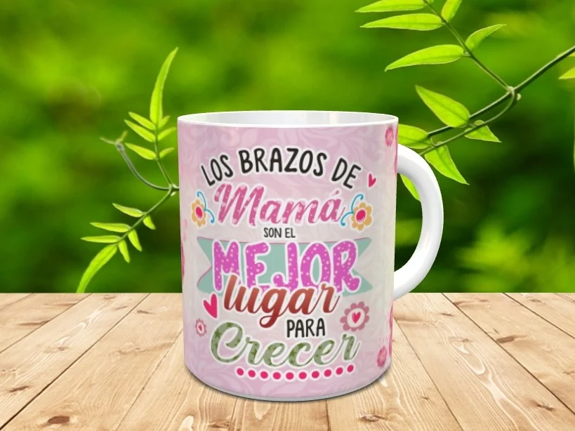Taza blanca de cerámica personalizada con un diseño rosa y el texto Los brazos de mamá son el mejor lugar para crecer sobre una mesa de madera.
