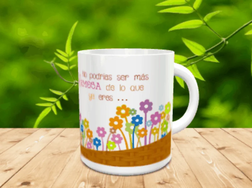 Taza blanca de cerámica con un diseño de cesto inferior lleno de coloridas flores y la frase No podrías ser más hermosa, sobre una superficie de madera.