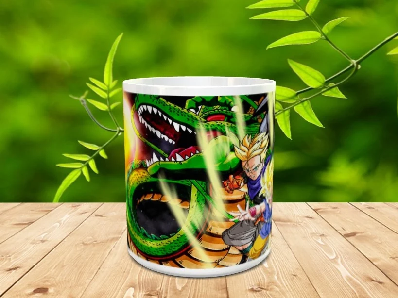 Taza de cerámica blanca decorada con la ilustración de un dragón verde y personajes de animación sobre una superficie de madera y fondo natural desenfocado.