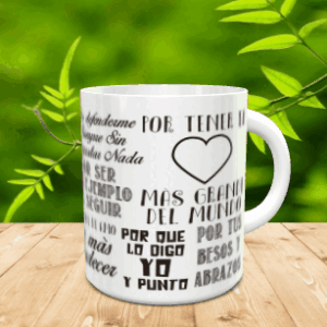 Taza blanca de cerámica con un diseño de collage de textos oscuros y un corazón, apoyada sobre una superficie de madera ante un fondo vegetal difuminado.