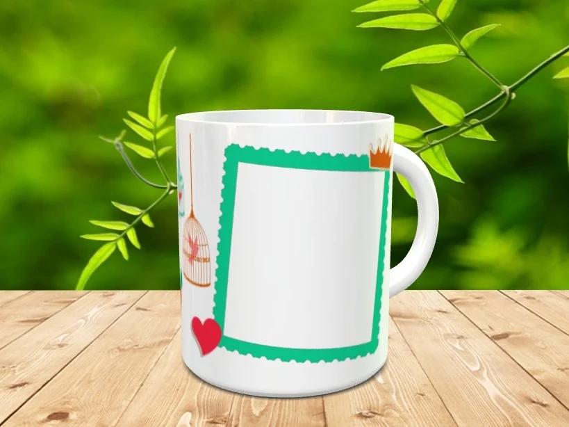 Taza blanca de ceramica con un marco verde festoneado preparado para personalizar con foto, junto a detalles de jaula y corazon sobre superficie de madera.