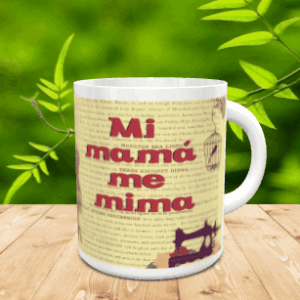 Taza blanca de cerámica con diseño vintage que muestra la frase Mi mamá me mima en tonos rojizos, sobre una superficie de madera.