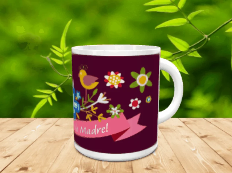 Taza blanca de cerámica en movimiento con fondo morado, un simpático pájaro, motivos florales y una cinta rosa con mensaje, situada sobre superficie de madera y fondo vegetal. Ref. mama-27x