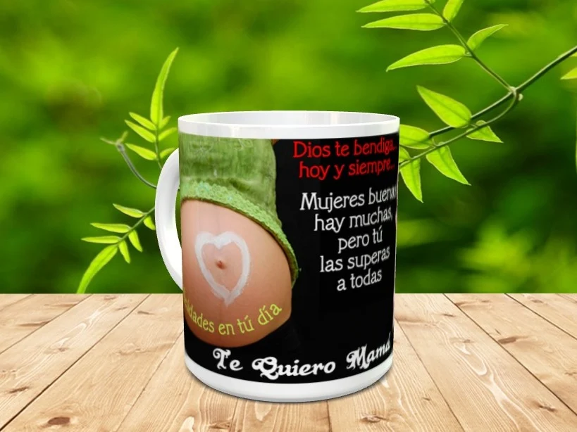 Taza blanca de cerámica personalizada con fotografía de vientre de embarazada y texto emotivo sobre fondo negro, situada en una superficie de madera.