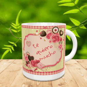 Taza blanca de cerámica decorada con un diseño de dulces, rosas y la frase te quiero mucho sobre una superficie de madera.