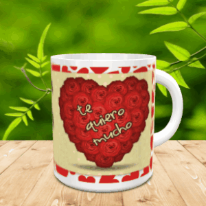 Taza blanca de cerámica con diseño de corazón formado por rosas rojas y la frase Te Quiero Mucho, sobre superficie de madera y fondo verde.
