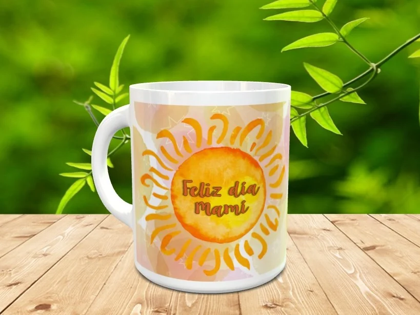 Taza blanca de cerámica para el Día de la Madre decorada con un diseño de sol sonriente y la frase Feliz día Mami, situada sobre madera con fondo natural desenfocado. Ref. mama-7xx