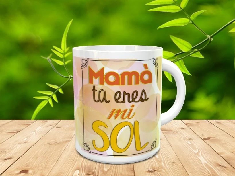 Taza blanca de ceramica decorada con un marco rectangular y el mensaje Mamà tù eres mi SOL. Se muestra sobre una superficie de listones de madera con fondo natural desenfocado.