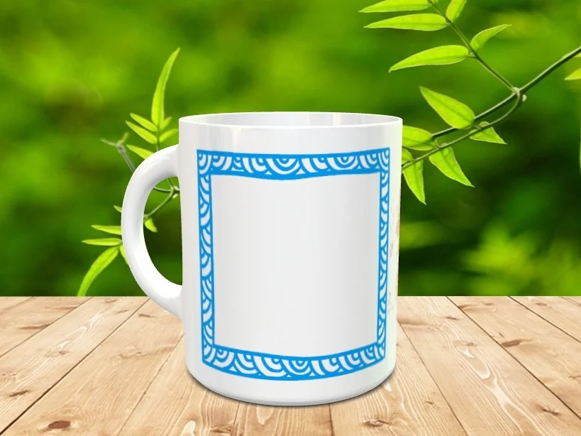 Taza blanca de cerámica con un marco cuadrado azul decorado con ondas y un espacio central blanco personalizable, situada sobre una superficie de madera con fondo vegetal.