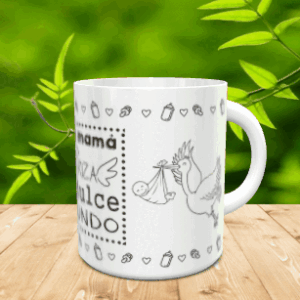 Taza blanca de cerámica para el Día de la Madre con diseño de cigüeña y bebé, situada sobre madera con fondo verde.