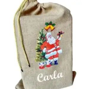 Fotografía de catálogo sobre fondo blanco de un saco de regalos de Papá Noel. Bolsa de tela de yute natural personalizada con la ilustración de Santa Claus y el nombre Carla en letras blancas.