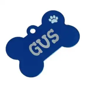 Fotografía de catálogo en perspectiva sobre fondo blanco de una placa azul oscuro para perro en forma de hueso. Se muestra el nombre Gus grabado con láser en letras blancas y el icono de una huella calada en la esquina superior.
